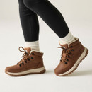 Brown winter hiking boots with cream fleece lining and chunky grip soles, worn with white socks and black leggings.