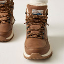 Front close-up of a brown winter hiking boot showing patterned laces, black metal eyelets, fleece-lined tongue and reinforced toe.