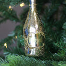 A close up view of a gold prosecco bottle hanging decoration hanging on a Christmas tree
