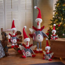 Multiple sized turkeys with red Santa hats next to a Christmas tree.
