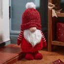 A mini red standing gonk with a Santa hat by a doorway,