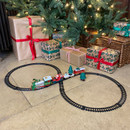 Christmas train set running around a decorated Christmas tree with wrapped presents, featuring a festive locomotive, Santa carriage and circular track layout.