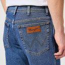 Close-up of the back pocket of blue jeans with a branded leather patch and stitching detail.