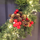View of a red berry and pine cone pick on a wreath