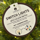 Switch-light Christmas tree feature label showing selectable warm white and multi-coloured LED lighting modes controlled by a remote function.