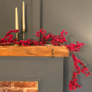 Red berry garland draped across a wooden mantel shelf, featuring clusters of realistic glossy berries for festive Christmas and winter décor.