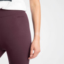 Close-up of a woman's hip and hand wearing plum-coloured leggings. The leggings feature a subtle "WEIRD FISH" logo near the waistband.