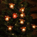 A close up image of a string of ten Christmas lights strung upon a Christmas Tree. Each warm white light lights up the nose of a brown felt reindeer with floppy ears. One reindeer is Rudolph whose nose is lit up with a red light.