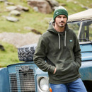 Man wearing a Ridgeline Ballistic Fleece, blue jeans and green beanie. He is leaning against a blue Land Rover Defender in front of a rocky hill.