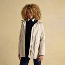 Woman wearing a beige hooded raincoat layered over a navy jumper and white shirt.