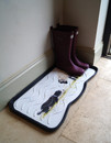 A tray in a hallway that has a pair of wellingtons stored on it, it has a sheep and and a dog meeting each other printed on it.