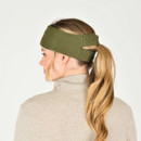 A woman from the back wearing an olive green knit headband with a Weatherbeeta logo on, her hair is in a ponytail and the ponytail has been pulled through a slot in the headband.