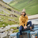 A woman sitting on a Land Rover defender in a yellow smock