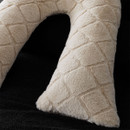 Close-up of a beige white, textured fabric in a diamond pattern against a dark background.