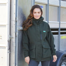 Woman standing in front of a Trailer. She is wearing a Ridgeline Rhea Jacket in a Deep Forest colour