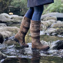 Person in brown boots stepping on water between rocks.