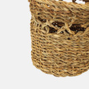 A close up view of a small handled seagrass basket on a grey background