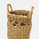A close up view of a small handled seagrass basket on a grey background