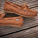 A close up view of a pair of walnut brown deck shoes on a wooden pier. A close up view of a pair of walnut brown deck shoes on a wooden pier.