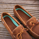 A close up view of a pair of walnut brown deck shoes, with aqua coloured panels A close up view of a pair of walnut brown deck shoes, with aqua coloured panels