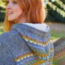 A close up of a woman showing the back of a grey zip up knit hoodie.