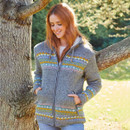 A woman standing under a tree with her hands in the side pockets, wearing a grey zip up knit hoodie with a multicolour fair isle pattern across the chest and bottom of the jumper.