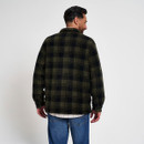 Rear view of a man wearing a green and black checked fleece jacket with blue jeans and a white checked shirt underneath.