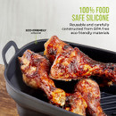 Grilled chicken drumsticks in a black silicone pan with eco-friendly labels.