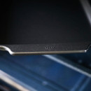 Close up of the edge of a black steel baking tray with a subtle crown logo visible.