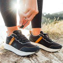 A woman wearing cinder coloured trainers walking along a cliff top