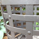 Close-up of a black metal fire basket with a blurred greenery background.