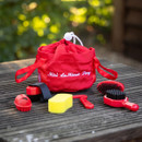 A red LeMieux toy pony grooming kit laid out upon a wooden table, displaying the red bag and all brushes and combs.