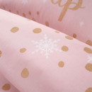 Close up of pink bedding with gold polka dots and a white snowflake pattern.