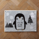 A cute penguin-themed bath mat on a herringbone wood floor.