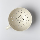 A cream coloured colander with a handle on a white background.