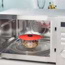 A glass bowl with rice inside a microwave with a red silicone lid.