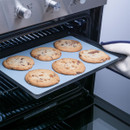 Freshly baked cookies on a tray and blue baking sheet inside an open oven.