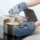 Hands in oven gloves lifting lid of a pot with potatoes on the stove.