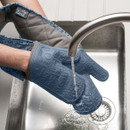 A pair of waterproof oven gloves being tested under running sink water.