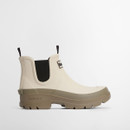 A side view of a cream wellington boot with a dusky green chunky sole and black elasticated side panels and pull tabs.