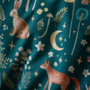 Close-up of teal woodland fabric featuring a rabbit, fox, crescent moon, stars and botanical details.