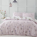 A view of a bed with a reversible pink bedding set with a floral bird bedding design