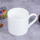 A white ceramic mug on a textured surface with a colourful figurine to the left.