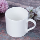 White mug on a wooden table with flowers in the background.