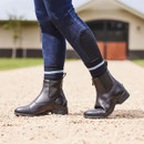 A person wearing dark jodhpur boots and blue jeans stands on a gravel surface. A person wearing dark jodhpur boots and blue jeans stands on a gravel surface.