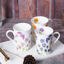 Three white floral-patterned mugs on marble surface with rustic backdrop.