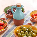 A blue and brown oil drizzled with cork stopper on a table surrounded by food