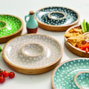 A wooden grey and white polka dot chip and dip bowl surrounded by different coloured of the same bowl