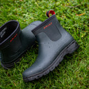 Navy waterproof boots with red "Ariat" logo on wet grass. The boots have a rugged texture and raindrops on their surface, conveying durability. Navy waterproof boots with red "Ariat" logo on wet grass. The boots have a rugged texture and raindrops on their surface, conveying durability.