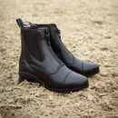 A pair of sleek black leather boots with zippers, placed on sandy ground. The boots convey a sense of elegance and durability.
